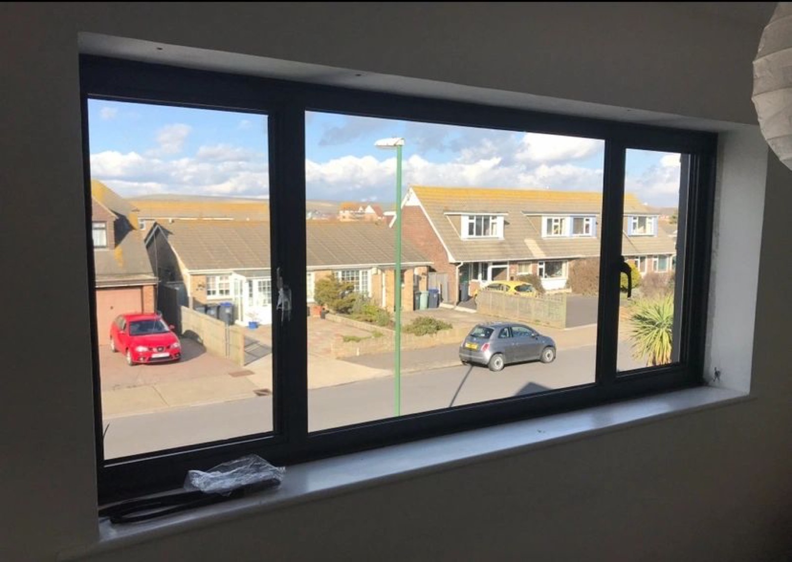 View through a newly fitted dark grey window onto a sunny street