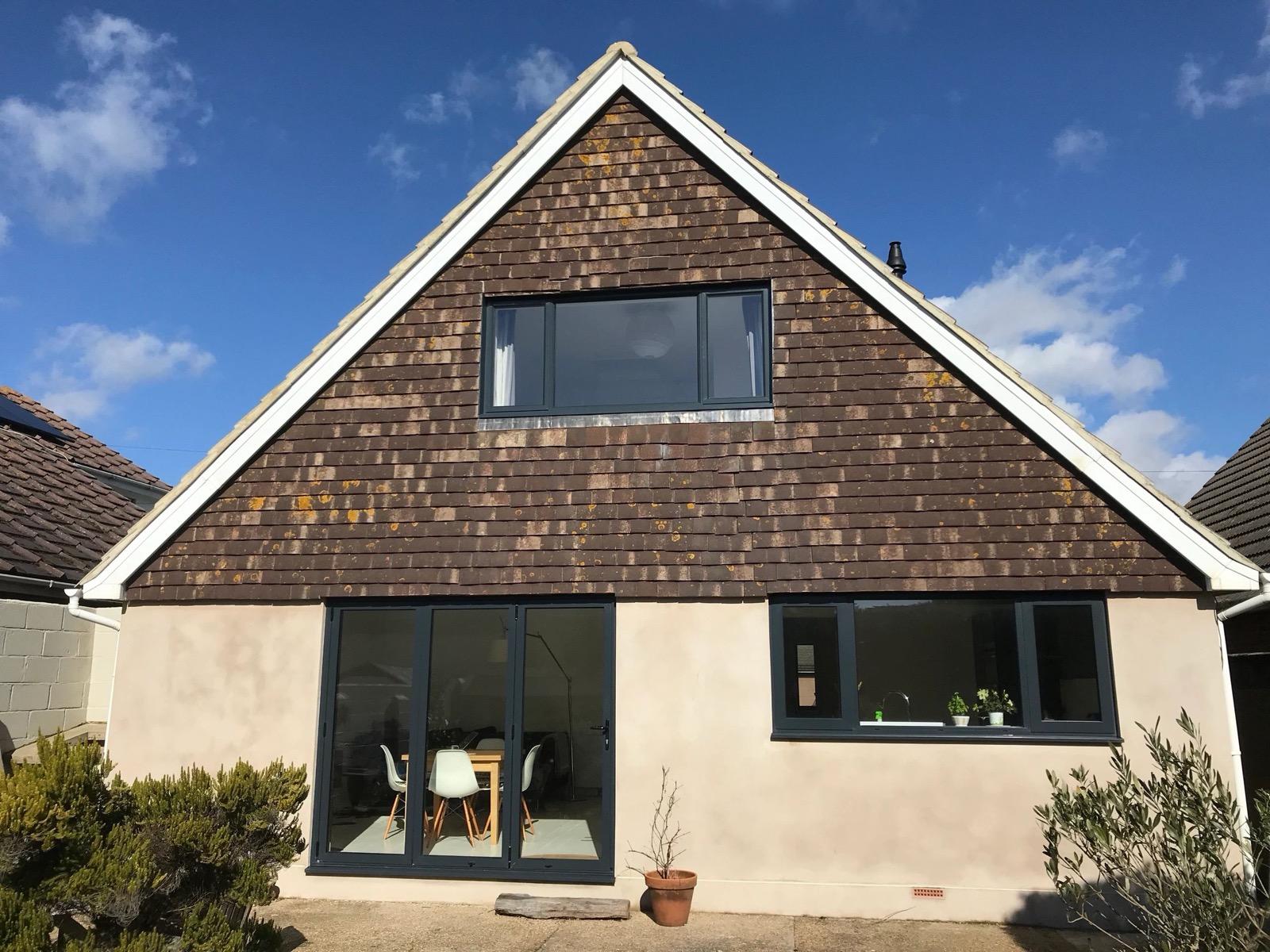 New dark grey aluminium bifold doors and windows on a tile-hung house